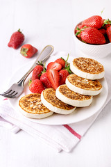 Homemade Cottage Cheese Pancakes with Ripe Strawberry on White Plate on White Wooden Background Tasty Healthy Breakfast or Lunch Vertical