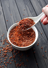 hand holdind a spoon with red rice pouring