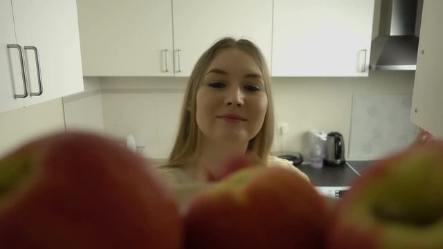 POV of attractive blonde hair young woman opens a cupboard and takes apple from a shelf. Healthy lifestyle.