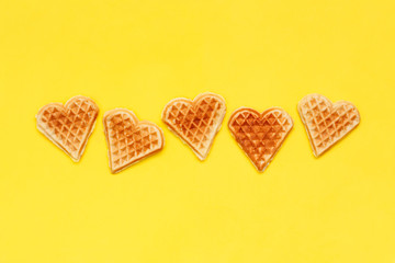 Card with crisp biscuit cookies waffles on yellow background. Shape of heart. For holidays Valentine's Day, Women's Day, Mother's Day. Row of homemade sweets. love food concept