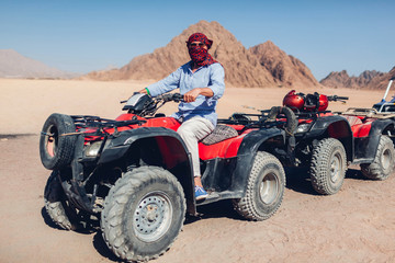 Senior man driving quad bike in Sinai desert. Happy tourist having fun during summer vacation