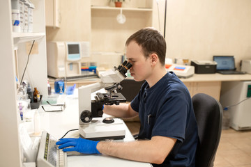 Laboratory assistant looking through microscope. Make research in laboratory. Science and medicine concept