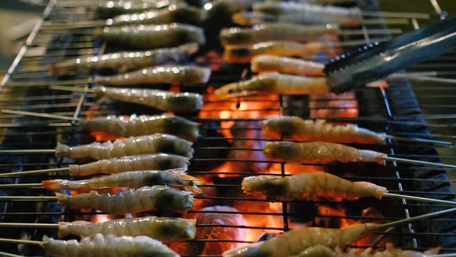 Fresh shrimp or prawn grilled bbq seafood on charcoal stove for night party. Royalty high-quality free stock video footage of grilling fresh prawns or shrimps on the flaming barbecue grill