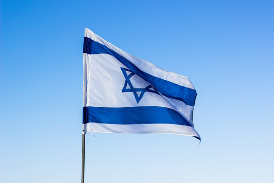 Israeli flag evolving in a wind on blue sky background, political country sign and symbols concept photography 