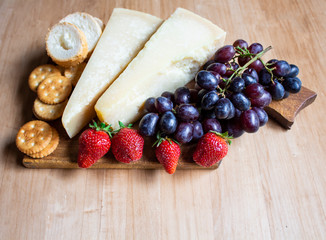 Cheese with grapes and strawberries, cracker, nuts, fruits and nuts. Cheese on a visible background. Copy space