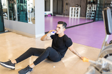 Exhausted Man Drinking Water In Gym