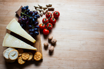 Cheese with grapes and cherry tomatoes, cracker, nuts, fruits and nuts. View from above. Cheese on a visible background. Copy space