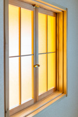 Traditional japanese house or ryokan with closeup of closed window door with transparent glass and yellow light