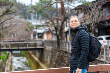 Fototapeta premium Takayama, Japan Small bridge by Enako river in Gifu prefecture in Japan with young man tourist in spring in traditional village