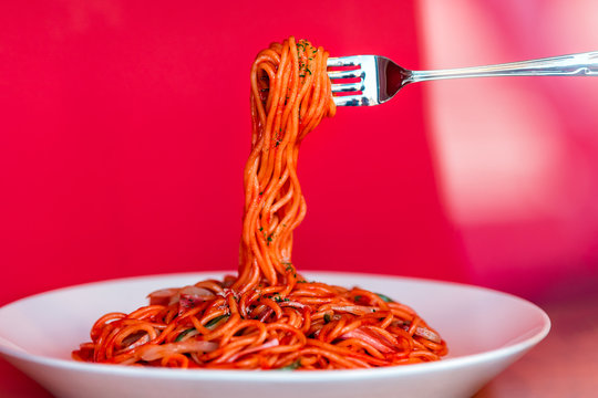 Closeup Of Red Sauce Italian Pasta Noodles With Fork Holding Basil On White Plate In Italian Italy Restaurant Or Studio