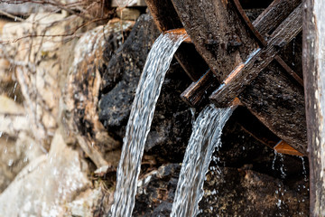 Takayama, Japan traditional wooden house building mill wheel with water running in Hida no Sato old folk village closeup