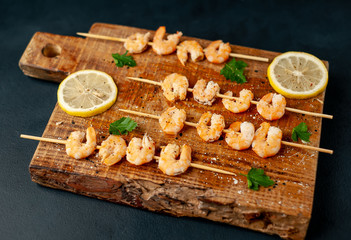 Grilled shrimp shashlik. shrimps with parsley and lemon on the background of concrete