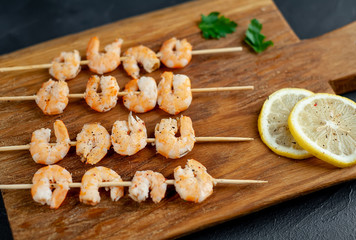Grilled shrimp shashlik. shrimps with parsley and lemon on the background of concrete