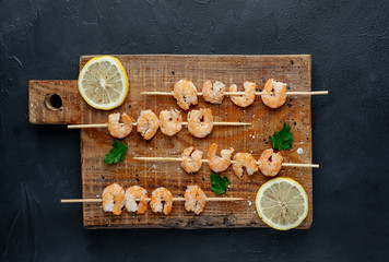 Grilled shrimp shashlik. shrimps with parsley and lemon on the background of concrete, with copy space for your text