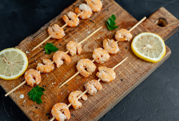 Grilled shrimp shashlik. shrimps with parsley and lemon on the background of concrete