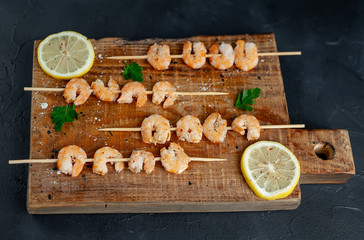 Grilled shrimp shashlik. shrimps with parsley and lemon on the background of concrete