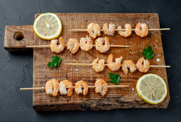 Grilled shrimp shashlik. shrimps with parsley and lemon on the background of concrete