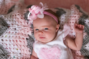 1 month old baby girl laying on crochet blanket on back