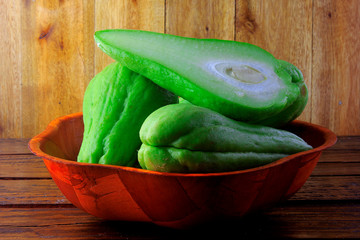 raw, fresh and organic chayote in basket on rustic wooden table