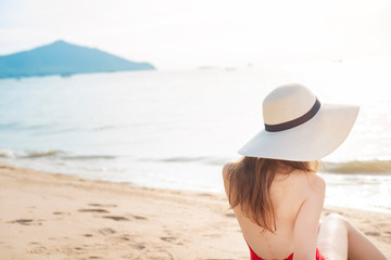 Back of Beautiful woman in red swimsuit is sitting on the beach