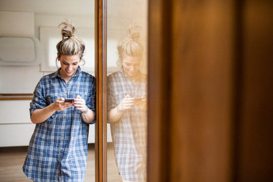 Beautiful and young woman having fun and chatting with the smart phone in her home