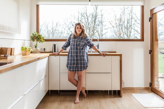 Portrait of blond young woman standing in kitchen at home