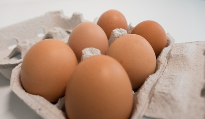 Carton of six eggs on a white table. Close up with shallow depth of field.