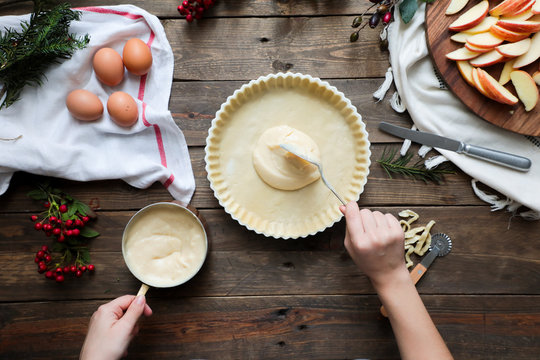 unrecognizable woman making a apple pie on a wooden table