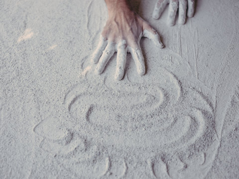 Hands of anonymous male artist spreading rough white plaster on plain surface in workshop