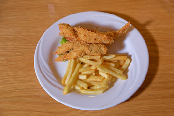 Fried pork chop with french fries . Fried chicken and french fries . Potatoes and chicken fries.