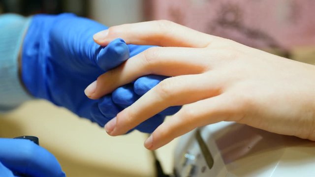 Close up shot the specialist in gloves treat the client's nail