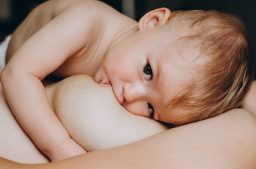 A Mother breastfeeding her little baby in her arms. close up mom nursing and feeding small kid....