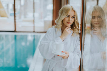 Beautiful young blonde woman relaxing at indoor swimming pool