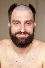 Obraz premium Portrait of man with an unusual hairstyle and beard with a naked torso, looks into the camera 