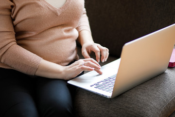 Pregnant woman working on laptop. Cropped image of pregnant businesswoman typing something on laptop while sitting at her working place in office