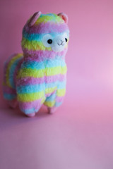 colorful rainbow Lama - soft children's toy on a pink background.