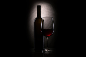 Still-life with the wine glass, red wine in a glass near to a bottle