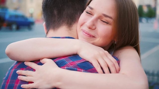 Love and relationship. Happy meeting. Young couple hugging in the street.