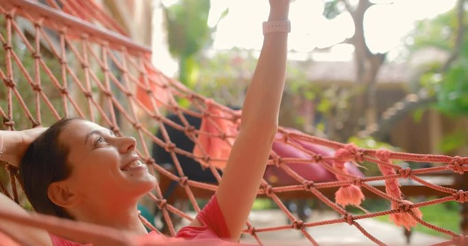 Attractive girl in a hammock takes a selfie on smartphone
