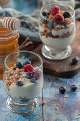 yogurt with granola and raspberries black chorynitsa and honey. yogurt in the blue on the table