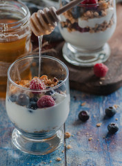 yogurt with granola and raspberries black chorynitsa and honey. yogurt in the blue on the table