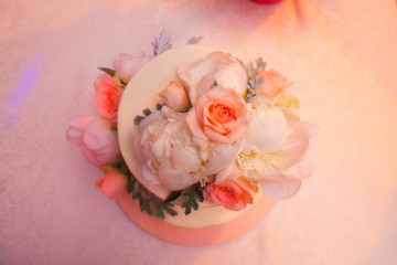 Wedding cake in pink decorated with flowers stands on the table