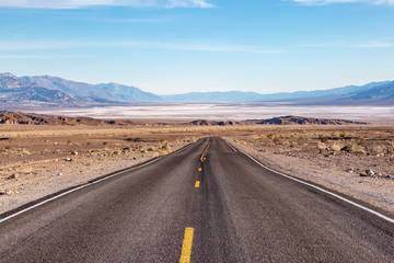 Looking down a road leading into Death Valley in California, with salt flats and a vast landscape ahead