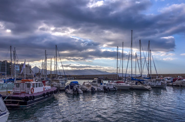 Fototapeta na wymiar Heraklion, Crete Island - Greece. View to the old Venetian port in Heraklion city full of fishing boats and yachts. Cloudy sky