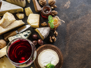 Cheese platter with organic cheeses, fruits, nuts and wine on stone background. Top view. Tasty cheese starter.