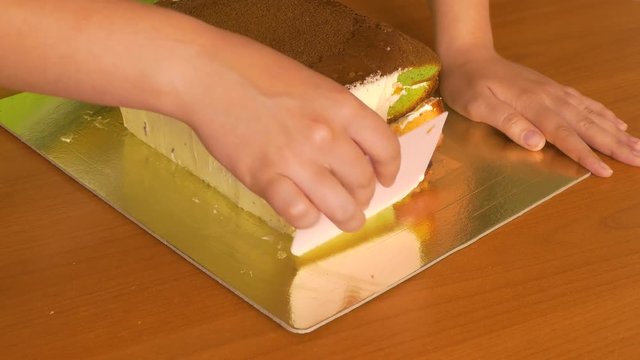 To grease with a cream with a special pastry knife of the side of a sponge cake with multi-colored cake layers