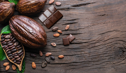 Cocoa pod, cocoa beans and chocolate on the wooden table. Top view.