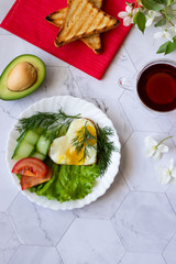 Fototapeta na wymiar Fried eggs with lettuce, cucumber and tomato slices on a light background