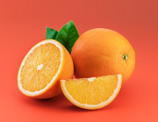 Orange fruit with orange slices and leaves isolated on orange background.
