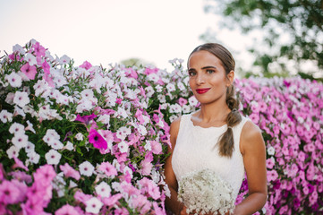 Beautiful bride shooting next to purple flowers and smelling them